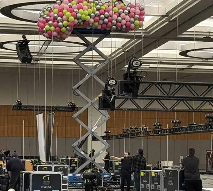 Scissor lift with crew setting up colorful balloon display for trade show, showcasing Elevate Exhibits event support services.