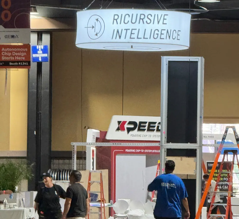 Large format hanging sign being installed above trade show booth at convention center by Elevate Exhibits rigging and installation team.