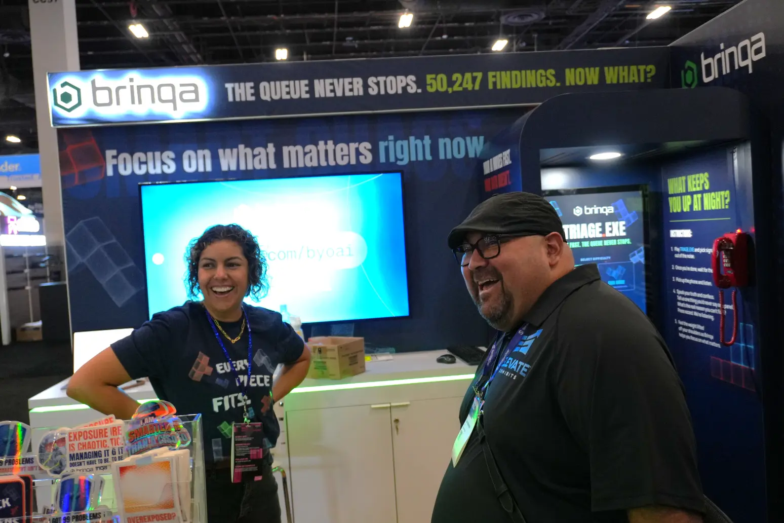 Brinqa team at cybersecurity conference booth, custom designed and built by Elevate Exhibits with LED backlit display and interactive stations.